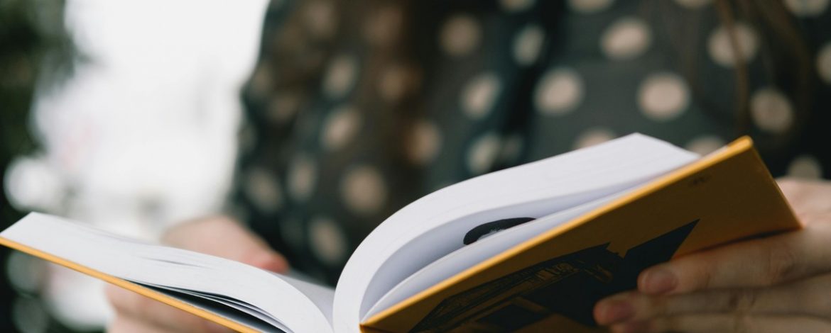 Person hält aufgeschlagenes Buch in den Händen – Manuskript überarbeiten für Selfpublisher