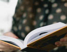 Person hält aufgeschlagenes Buch in den Händen – Manuskript überarbeiten für Selfpublisher