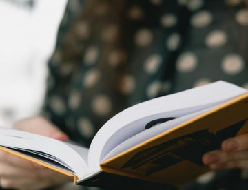 Person hält aufgeschlagenes Buch in den Händen – Manuskript überarbeiten für Selfpublisher