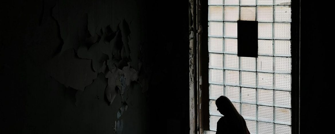 Person Frau vor Fenster Düster