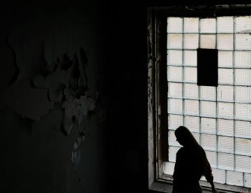 Person Frau vor Fenster Düster