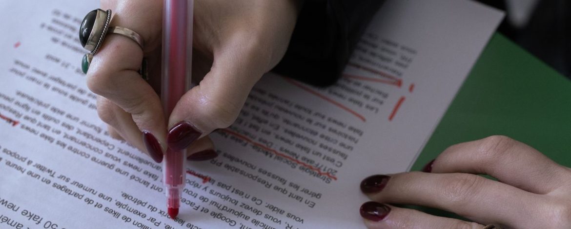 Hand korrigiert einen Romantext mit rotem Stift