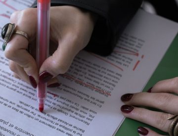 Hand korrigiert einen Romantext mit rotem Stift